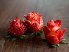 three strawberries are sitting on a wooden table