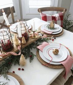 a table set for christmas with candles, plates and napkins on top of it