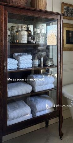 a display case filled with lots of white towels in a bathroom next to a toilet