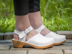 Slippersworld Handcrafted Low Heel White Swedish Clogs are perfect for everyday wear but also for special occasions. Our Swedish Leather and Wooden Sole Clogs Sandals with Buckle Strap can fit with so many foots and  items, with 7/8 denim leggings, with black yoga pants, summer dresses, and most definitely with a smile and a pep in your step.   Our Leather Moccasins Clogs Shoes for Women are unique and firm with alder wood platform sole, and covered with natural leather uppers, from selected hig White Mules With Heel Loop And Round Toe, White Closed Toe Clogs With Removable Insole, White Clogs With Removable Insole And Open Heel, White Clogs With Wooden Heel For Summer, White Clogs With Wooden Open Heel, White Open Heel Clogs With Removable Insole, White Closed Toe Clogs With Rubber Sole, White Open Toe Clogs With Leather Sole, White Clogs With Leather Sole And Round Toe