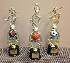 three trophies with different sports themed items on top of each other and one is holding a basketball