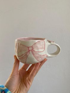 a hand holding a cup with a bow on it