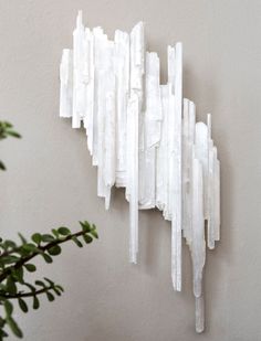 a white sculpture on the wall next to a potted plant