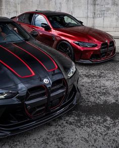 two cars parked next to each other in a parking lot, one is red and the other is black