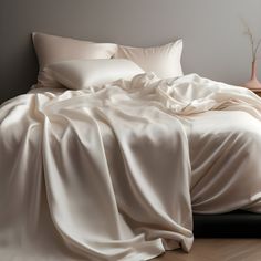 an unmade bed with white sheets and pillows