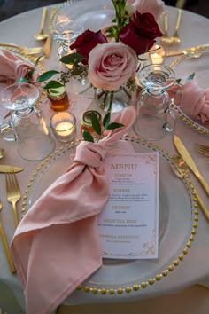 the table is set with pink flowers and place settings for an elegant dinner or party