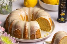 a bundt cake with icing sitting on a plate next to some lemons