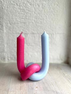 a pink and blue candle sitting on top of a wooden table next to a white wall