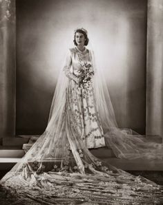 an old photo of a woman wearing a wedding dress and veil with flowers on it