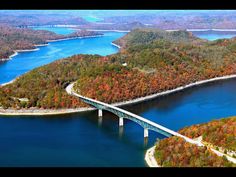 an aerial view of a bridge over a body of water surrounded by wooded hills and trees