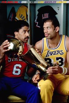 two men sitting next to each other with trophies in their hands and one holding a basketball trophy