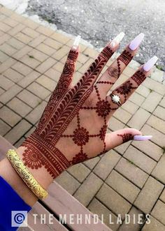 the hand with henna on it is decorated with gold and white decorations, which are accented with jewels