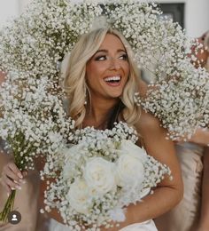 a woman holding a bouquet of flowers in front of her face and smiling at the camera