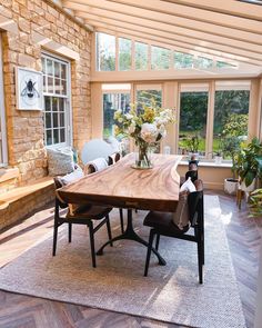 a wooden table sitting in the middle of a room with lots of windows on it