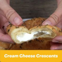 two hands holding a piece of bread with cream cheese on it