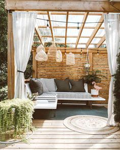 an outdoor seating area with white curtains and plants