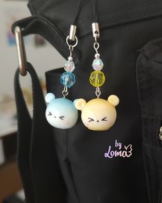 two little bears are hanging from the back of a bag with earring clips attached to them