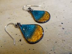 a pair of blue and yellow earrings sitting on top of a table