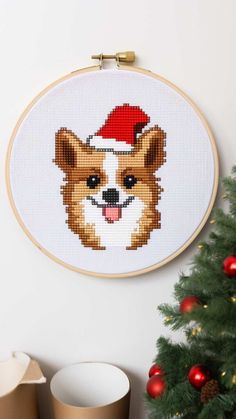 a cross stitch christmas ornament with a dog wearing a santa hat