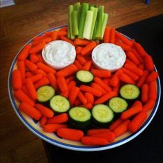 a plate with carrots, celery and cucumbers arranged to look like a face