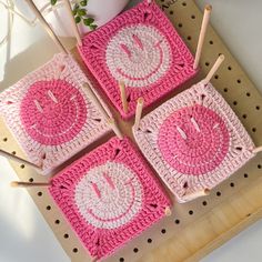 four pink crocheted coasters sitting on top of a wooden table next to a plant