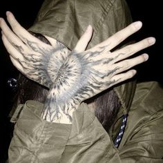 a person with tattoos covering their face and hands in front of her is wearing a green jacket