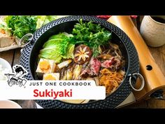 a bowl filled with lots of food next to chopsticks and other items on a table