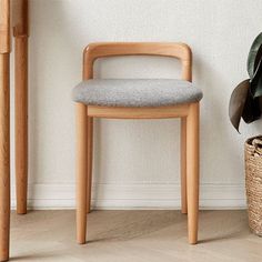 a chair next to a potted plant in a room with white walls and wooden flooring