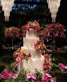 a three tiered wedding cake decorated with flowers and chandelier hanging from the ceiling