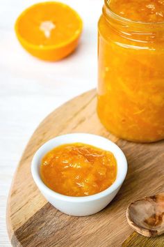 a jar of orange marmalade sitting on top of a wooden cutting board