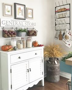 a white cabinet sitting next to a wall filled with pictures and other things on top of it