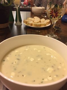 a bowl of soup sitting on top of a table next to a plate of bread