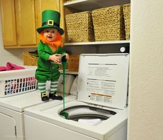 a little leprechan standing on top of a washer in a laundry room