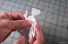 a person holding a paper cut out of a fairy