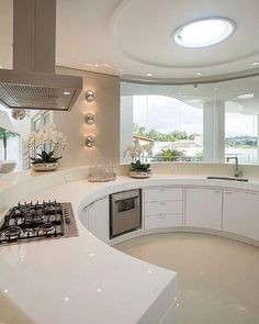 a modern kitchen with white cabinets and counter tops, along with an island in the middle