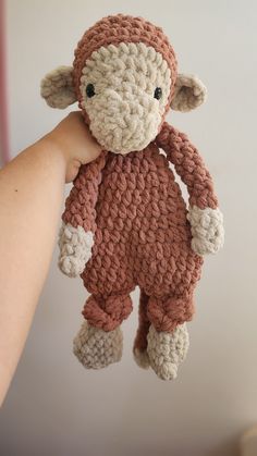 a crocheted monkey hanging from the ceiling in someone's hand with it's eyes closed