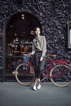 a woman standing next to a red bike