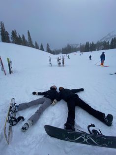 two snowboarders are laying on the ground with their skis in front of them