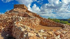 an old stone structure sitting on top of a rocky hill under a cloudy blue sky