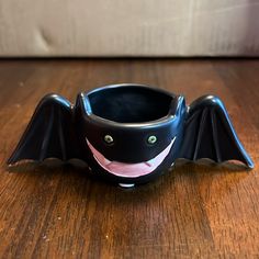 a black bat shaped cup sitting on top of a wooden table