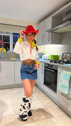 a woman wearing a cowboy hat and boots in a kitchen with tile flooring on the floor