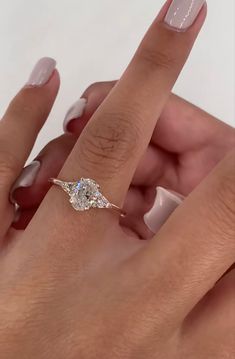 a woman's hand holding an engagement ring with a diamond on it and two fingers