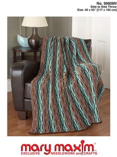 a couch with a blanket on top of it next to a lamp and chair in front of a wall