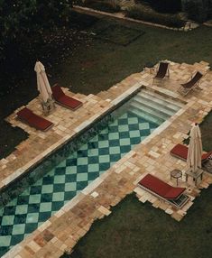 an aerial view of a swimming pool with lounge chairs and umbrellas