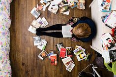 a person is laying on the floor surrounded by books and magazines that are scattered around them