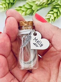 a person holding a tiny glass bottle with a bird charm on it's side