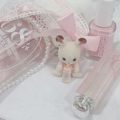 a teddy bear sitting next to a bottle of nail polish and some pearls on a table