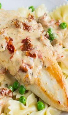 chicken with creamy sauce on top of pasta and peas in a white bowl, ready to be eaten