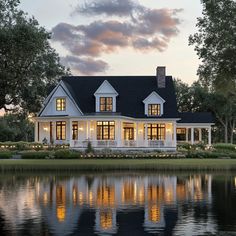 a large white house sitting on top of a lush green field next to a lake