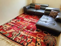 a living room filled with black leather couches and colorful rugs on the floor